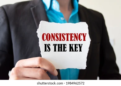 Person holding a sign that says “Consistency Is the Key”.